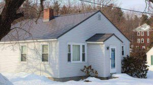 A small grey house with a brown metal roof in New Hampshire.