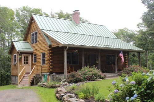 A pitched green metal roof on a log cabin in MA, CT, NH, or RI