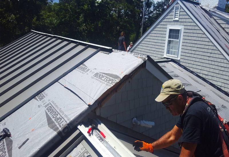 The man doing the sealing metal roof work