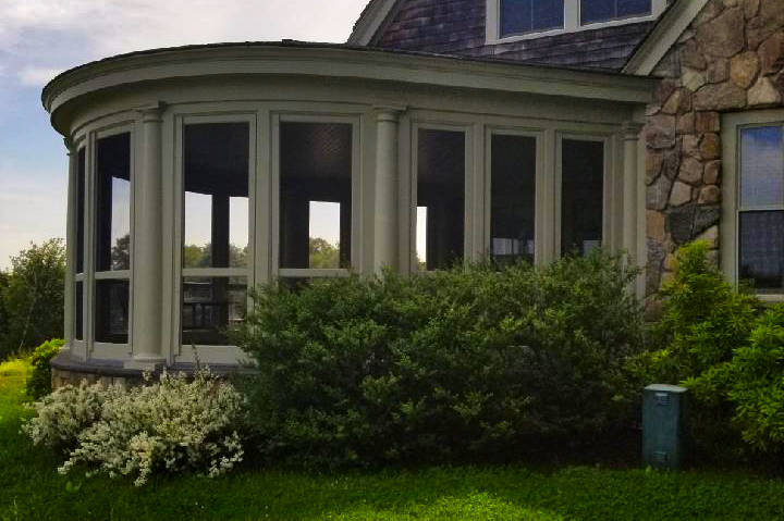 A house with a metal roof and tidy plants and shrubs in front of it in CT, MA, NH, or RI