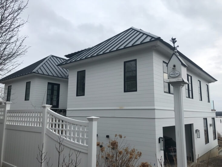 Dark metal roof on white 2-story house in RI