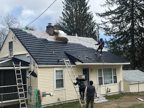 A roofing contractor installs metal roofing sheets in New England