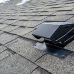 A static vent installed on a shingle roof for passive attic ventilation in New England