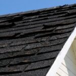 Loose asphalt shingles on a roof in New England.